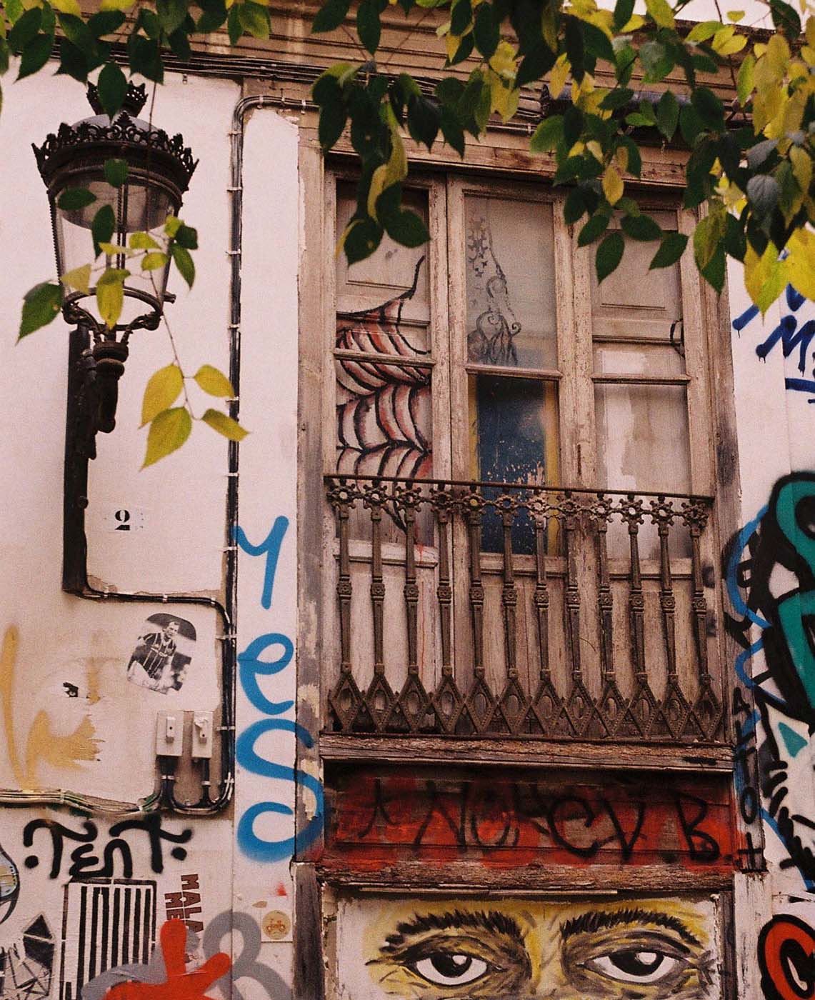 Old house façade with balcony, graffiti and street lamp