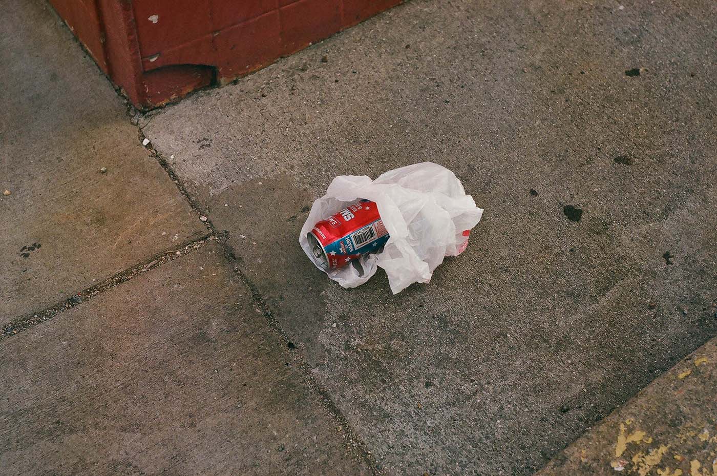 Empty can with USA symbols wrapped in plastic on the pavement