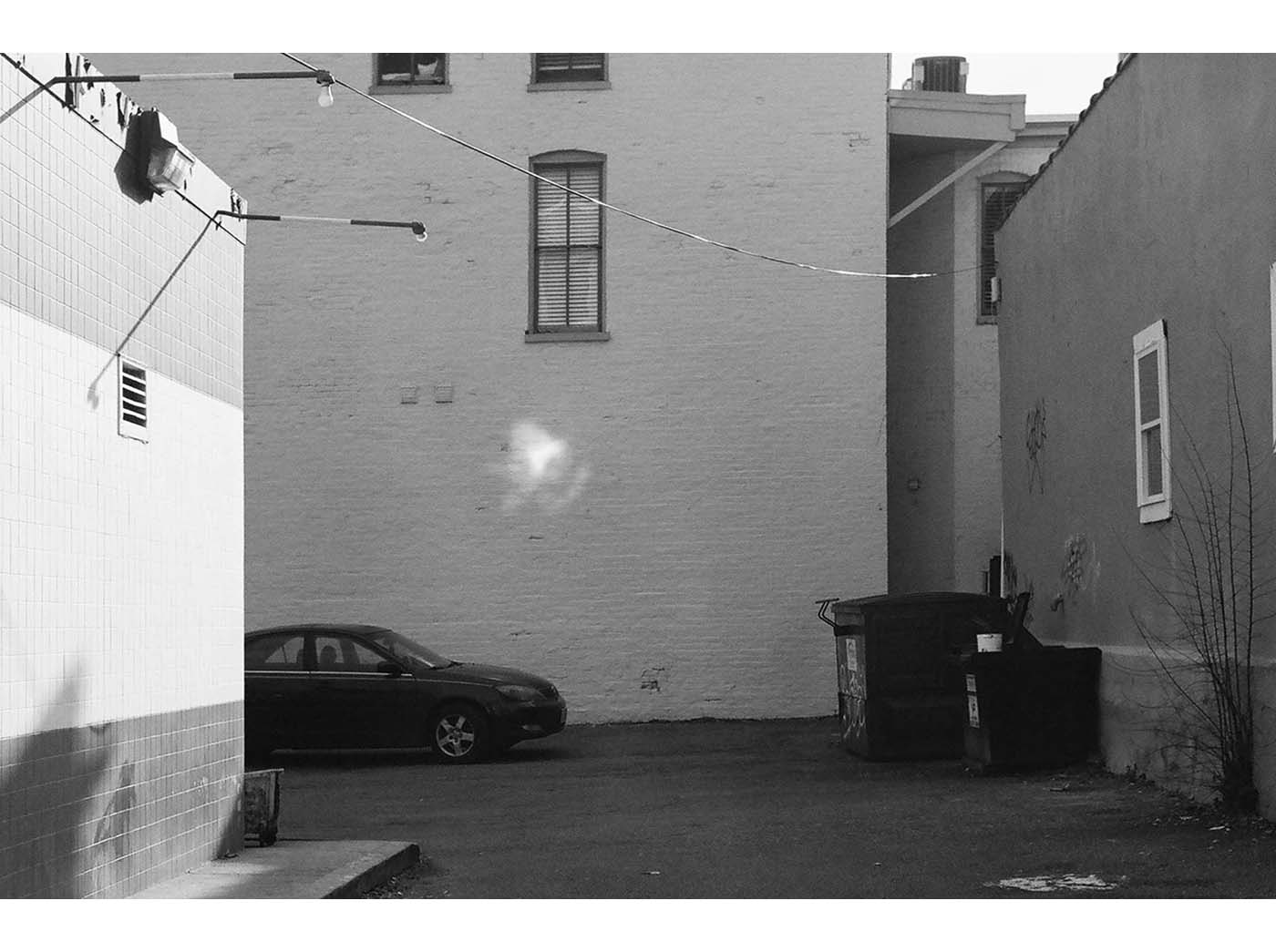 Alley with car, containers and light reflection on wall